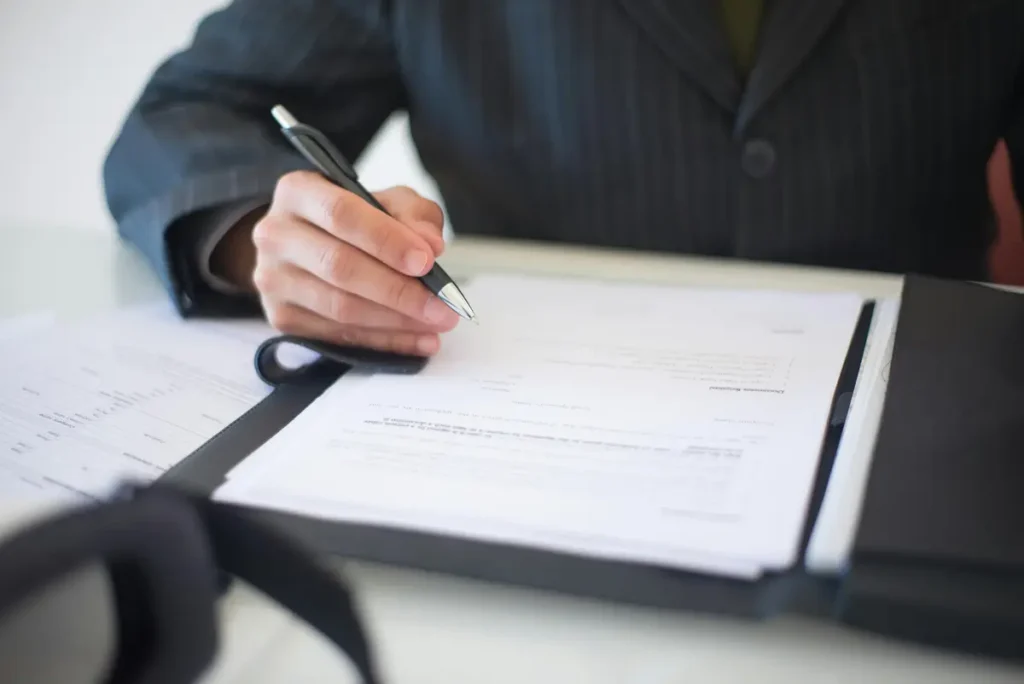 A close-up of a professional signing a legal document, representing the precision and clarity of Article 9 collateral verification.